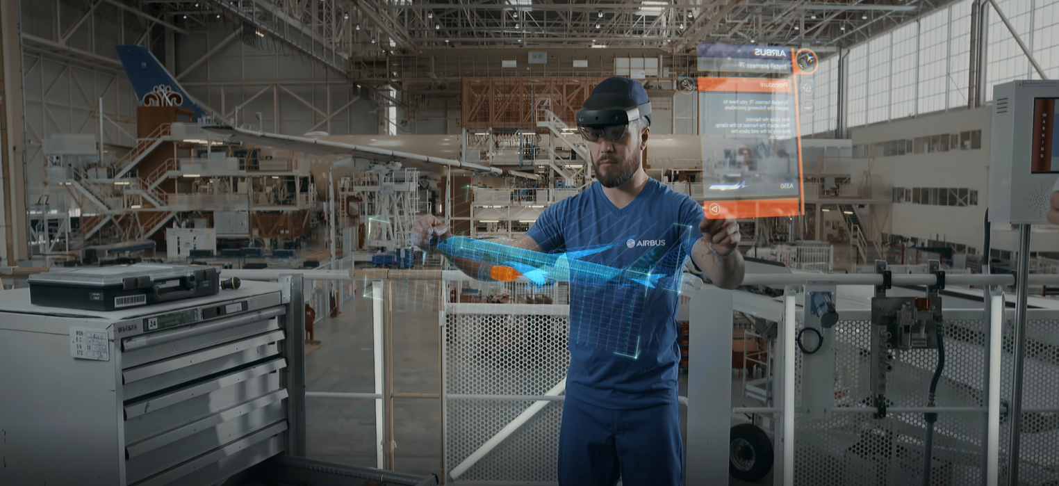 A man wears a HoloLens headset while mixed reality images are shown next to him in space.