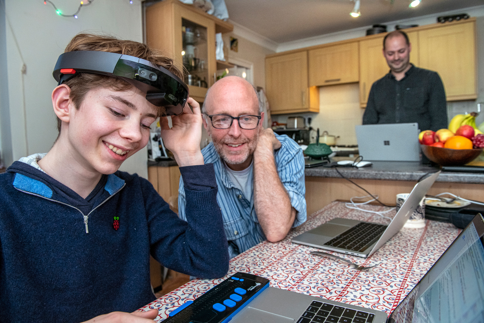 A child and two men use laptops