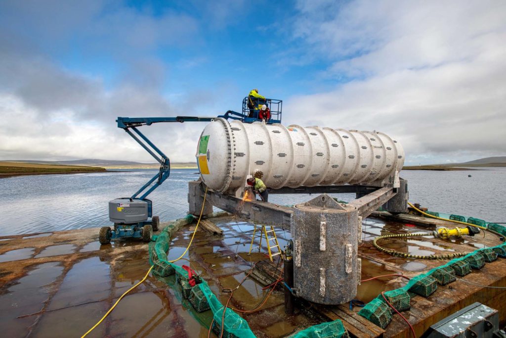 The Northern Isles datacenter being cleaned by two people on top in a bucket lift, and a person cuts the datacenter from its base