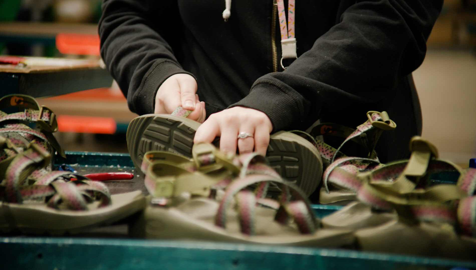 A worker's hands tinker with shoes.