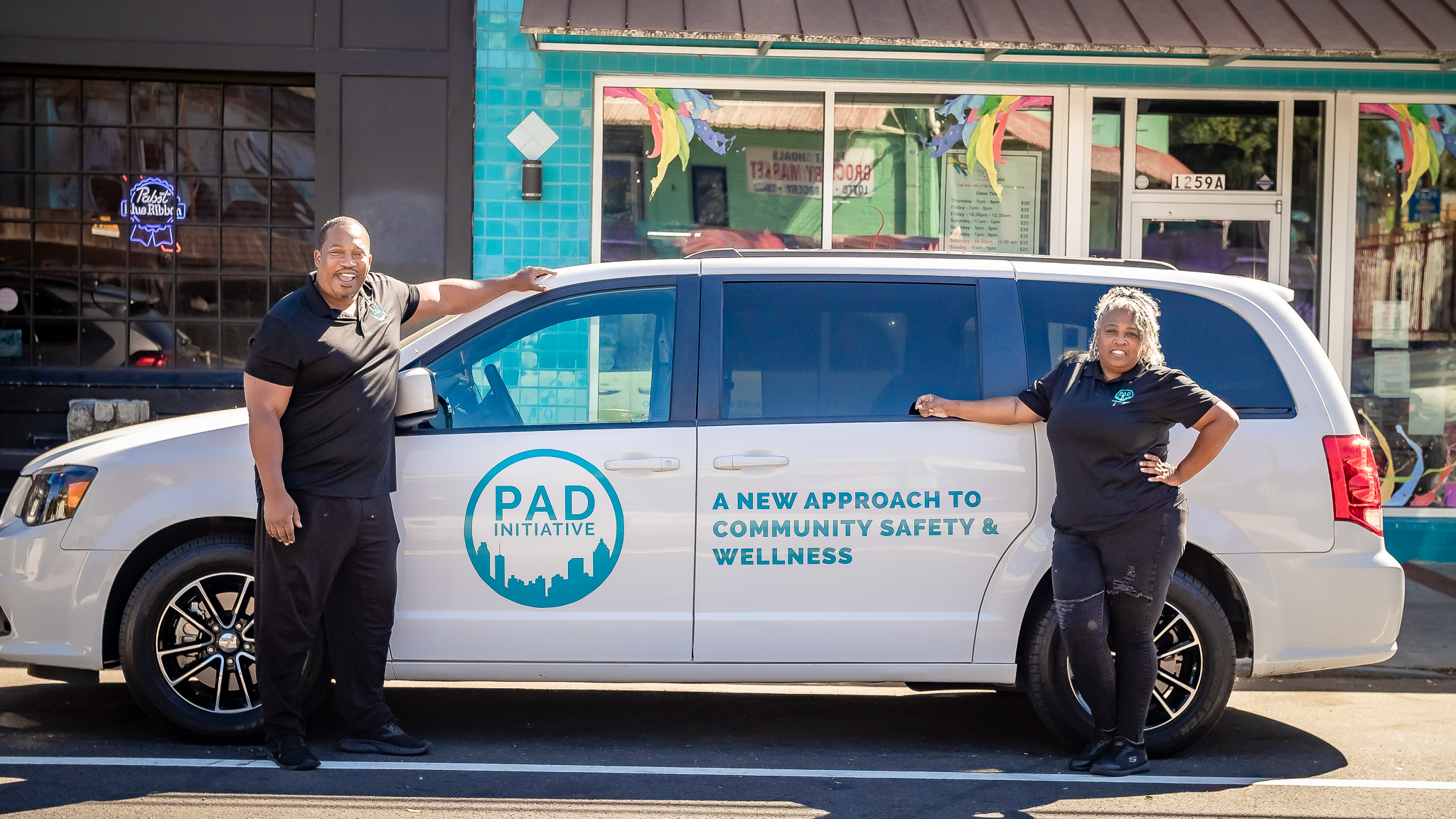 Man and woman stand by a car that reads 