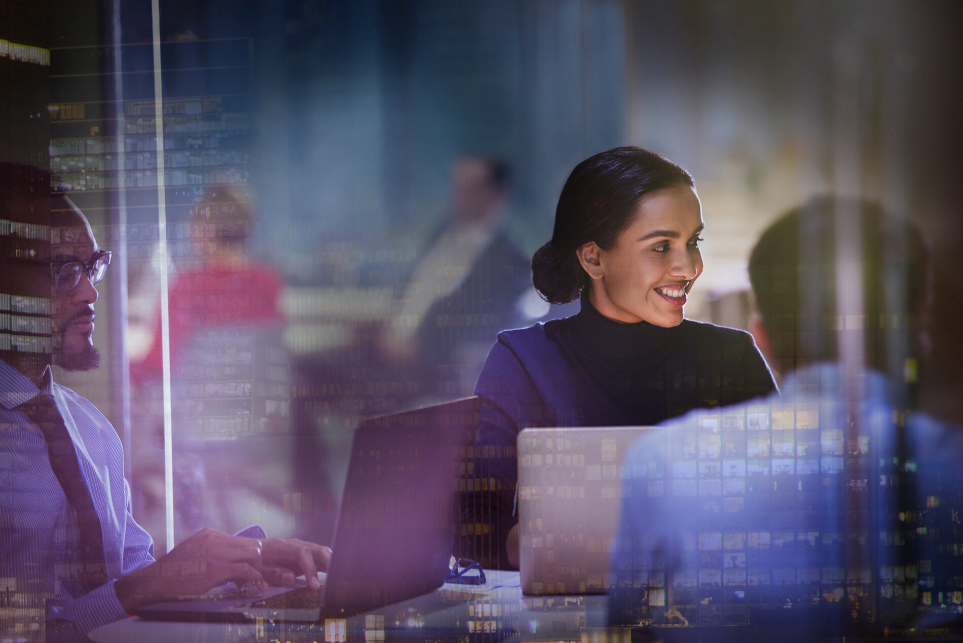 Stock photo showing people working in front of computer screens in an office setting.