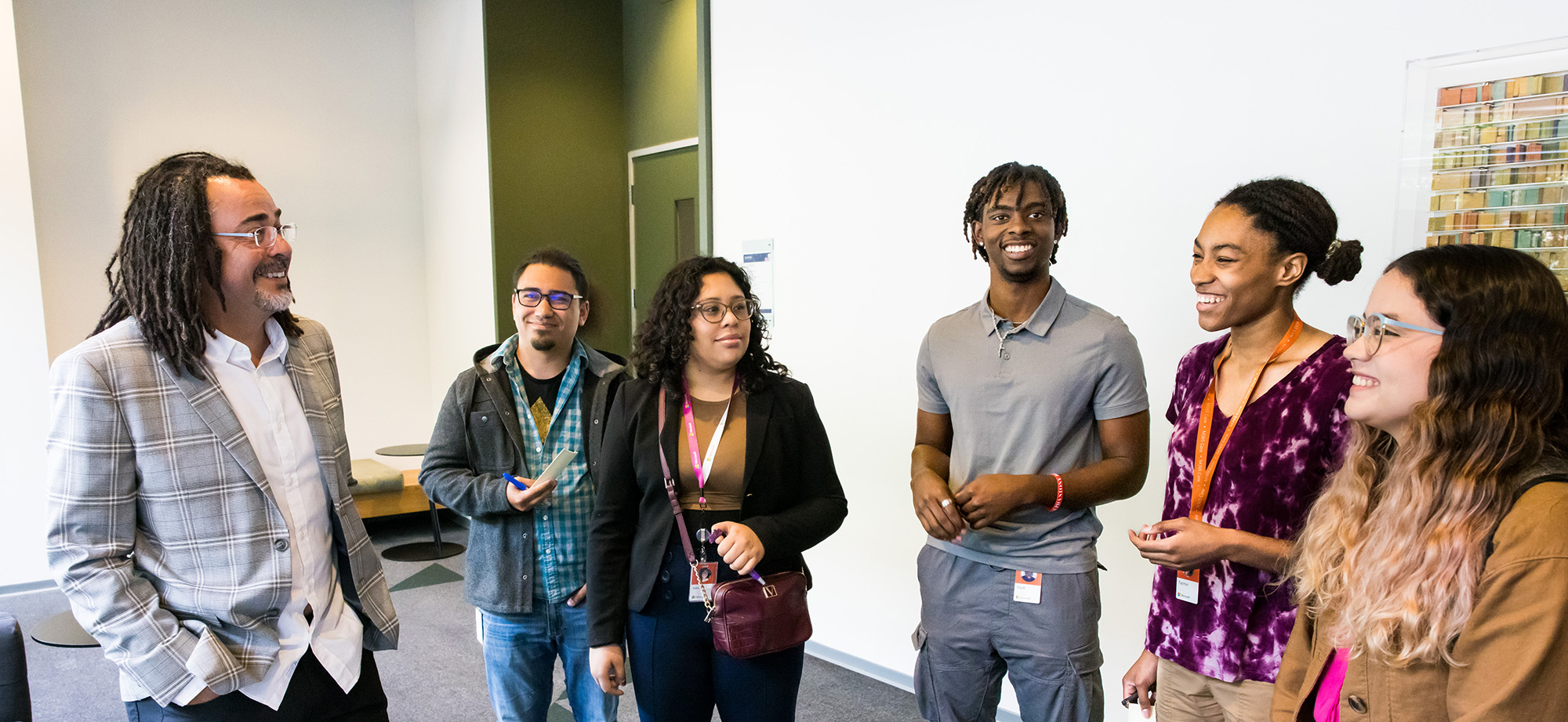 Six people standing together and chatting in an office building