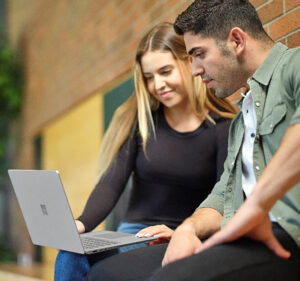 Woman and man viewing what's on a laptop computer