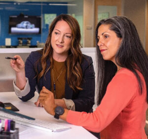 Two women discuss what's on a computer screen