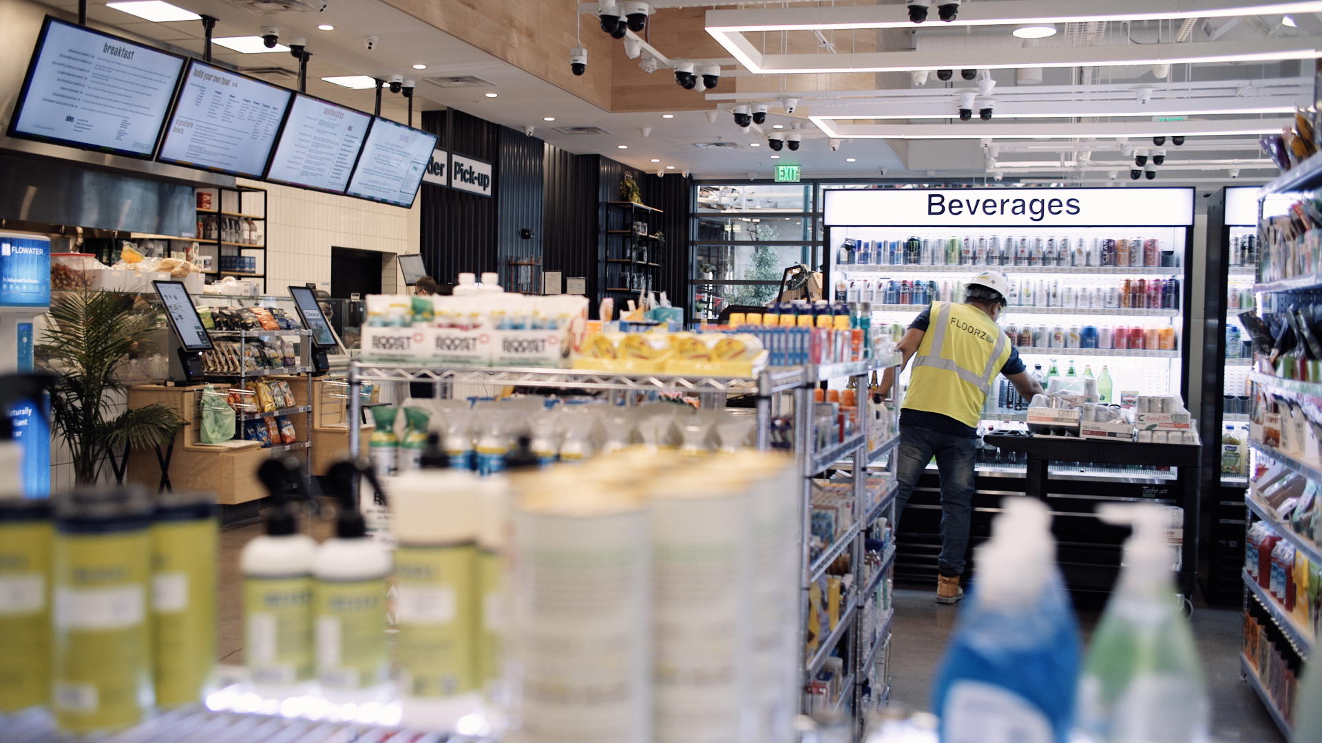 Photo inside a Choice Market convenience store, with a man in a construction vest and hard hat choosing a cold beverage in the background. 