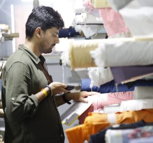 Photo of a man pointing a phone scanner at a label on a roll of fabric stacked in a shelf