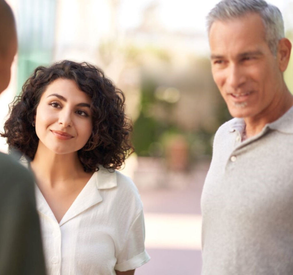 Woman and man conversing with a man whose back is toward the camera