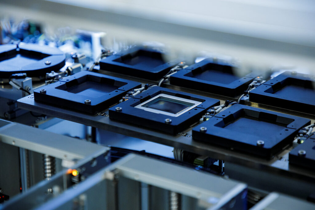 A machine featuring rows of square plates with a chip nestled inside one of the plates for testing.