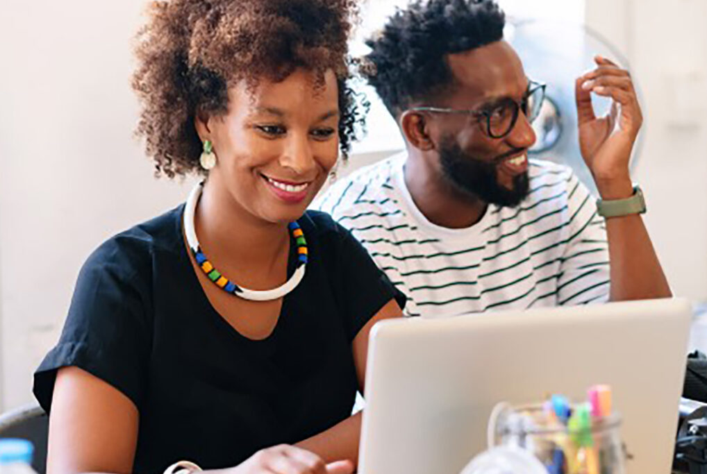 Woman and man smile as she works at her laptop computer