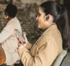 Woman holding a phone and listening to her earbud