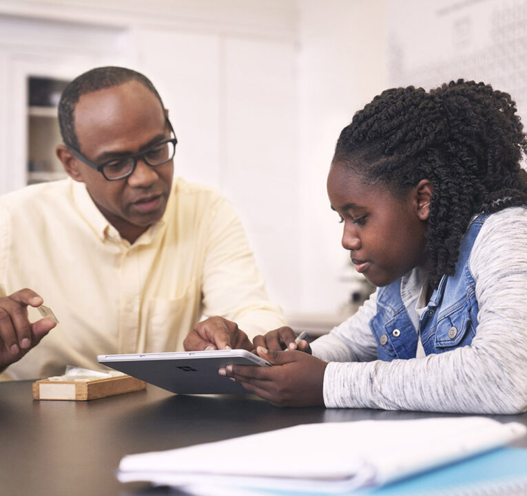 Black teacher and student working together on a tablet device