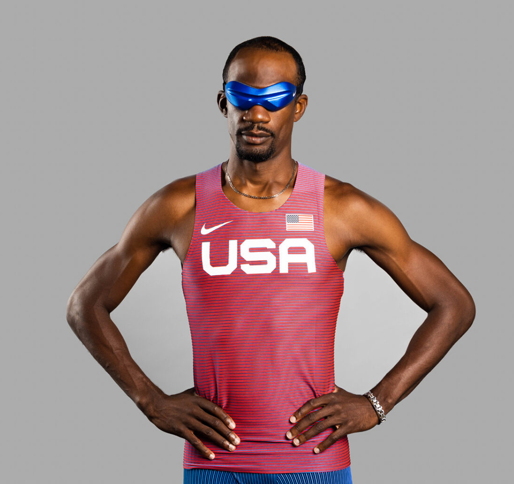 Man with arms akimbo wearing sunglasses and a running shirt with USA on the front