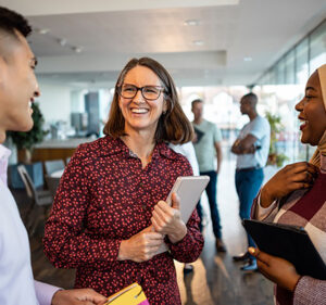 Three people standing in an office building, enjoying a conversation