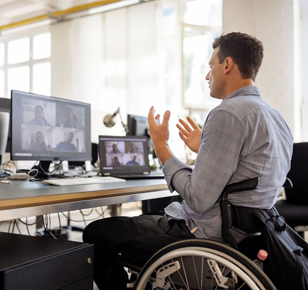 Man in a wheelchair attending a Teams meeting on a laptop computer
