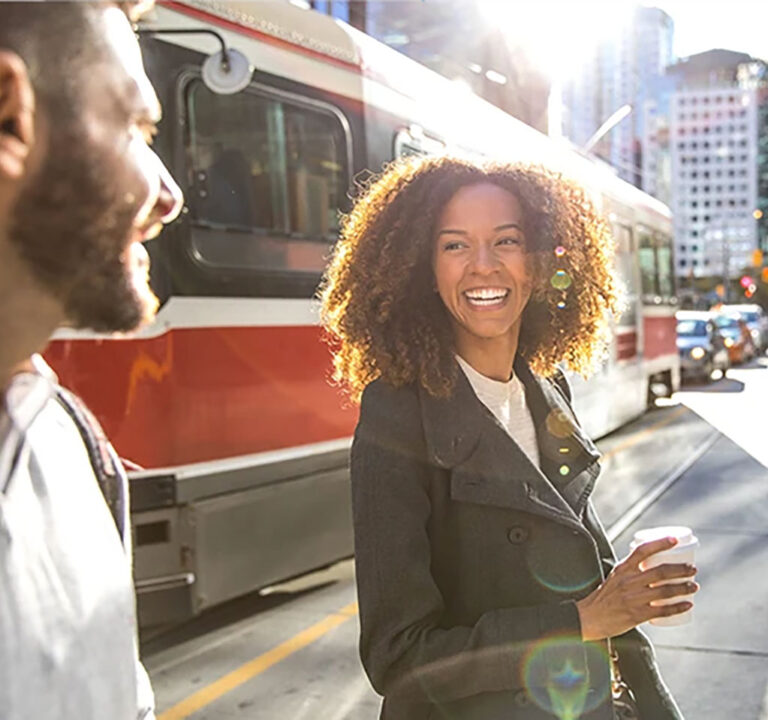 Woman and man talking on a city street as a bus drives by