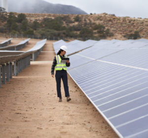 Woman in a hardhat inspecting solar panels