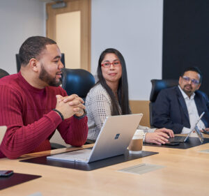 Three people seated at a table in a conference room