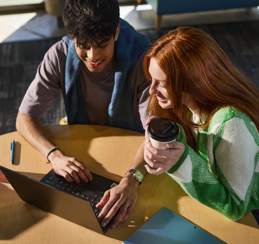 Young man and woman sharing a laptop computer at an outdoor cafe