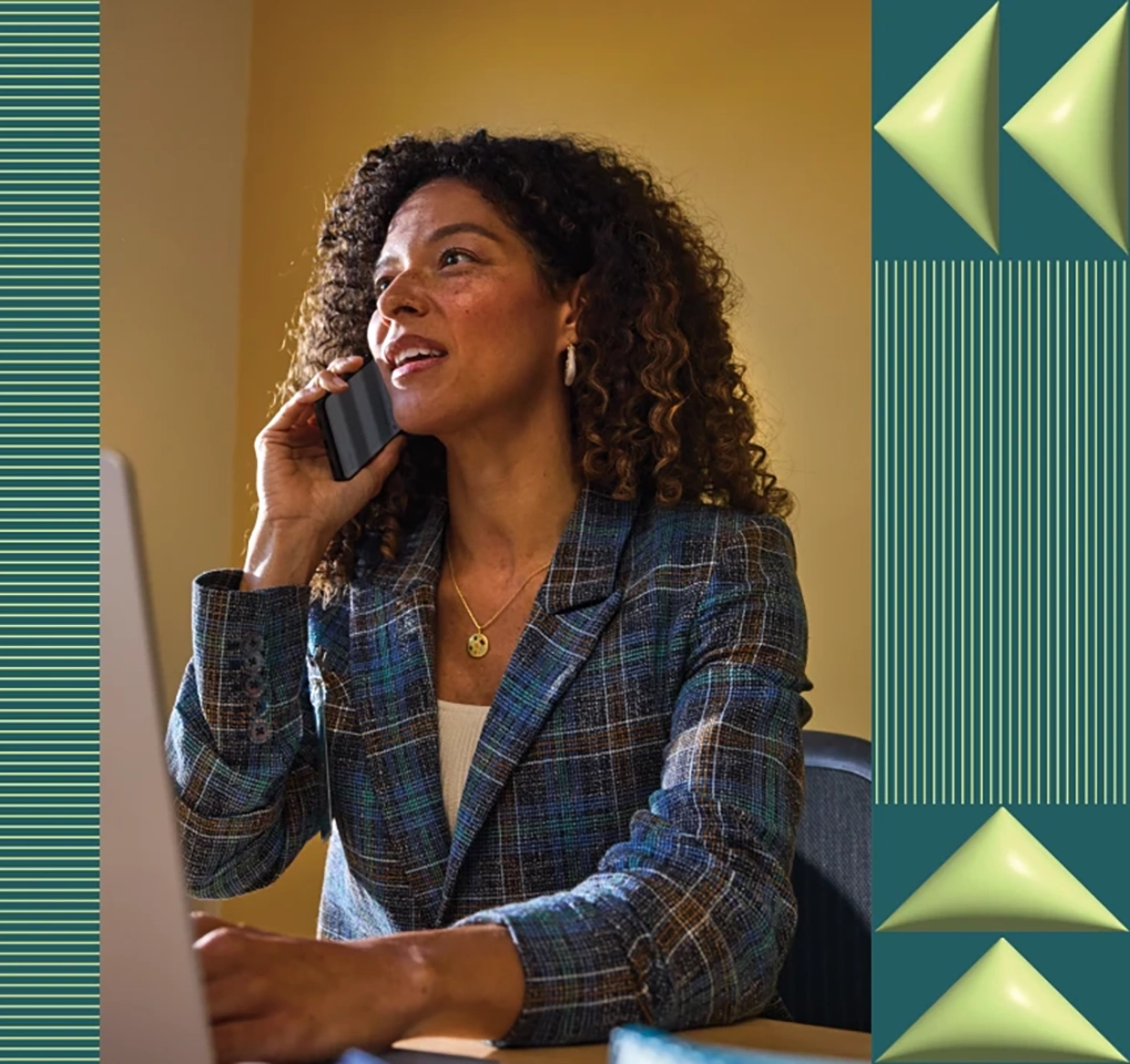 Woman talking on a phone while working on a computer