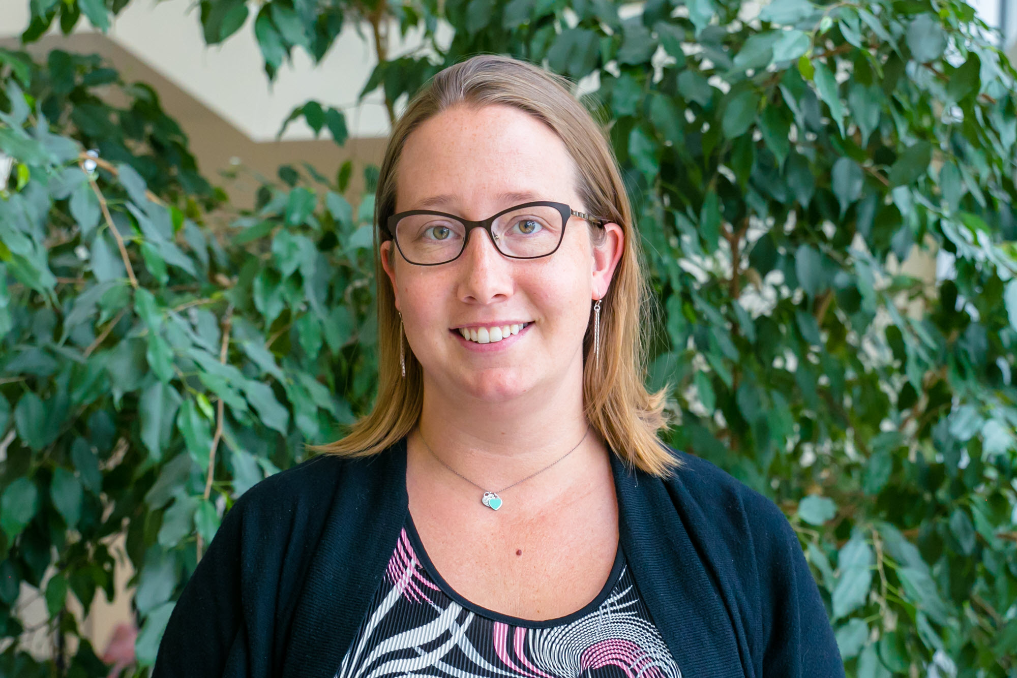 Carrie Jost, Arapahoe Libraries supervisor of creative spaces, standing in area with greenery in background. 