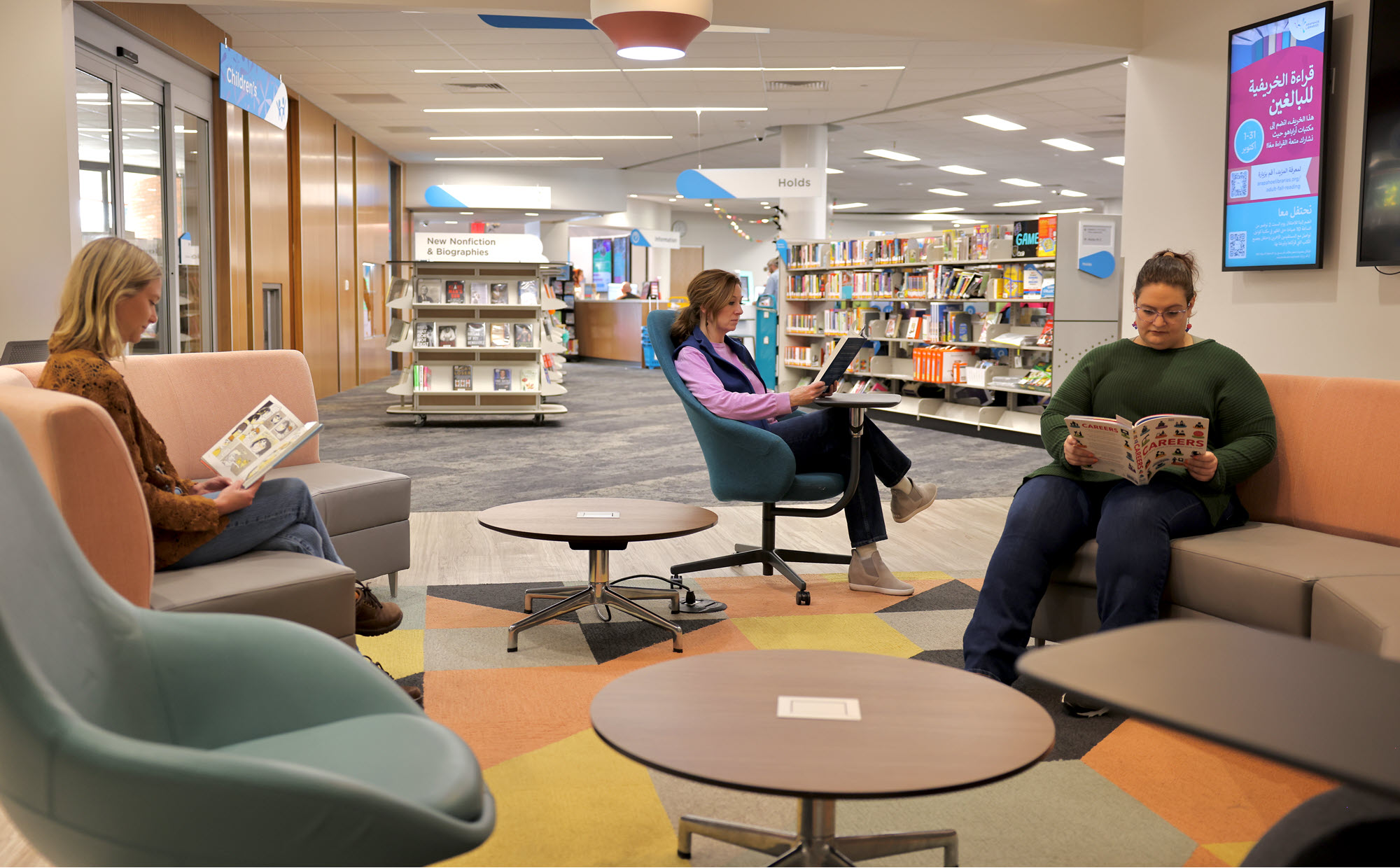 Three women sitting and reading in the lounge area of a public library. 