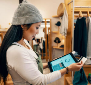 Profile photo of a woman holding a tablet device and a credit card in a retail store