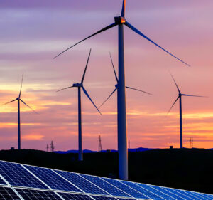 Wind power turbines and solar panels against a sunset background