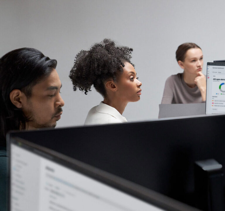 Three people working at desktop computers