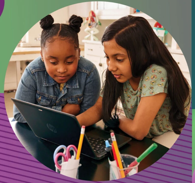 Two girls sharing a laptop computer in a classroom