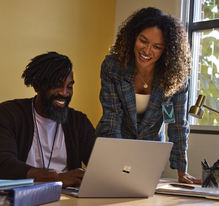 Two people looking at what's on a laptop computer.